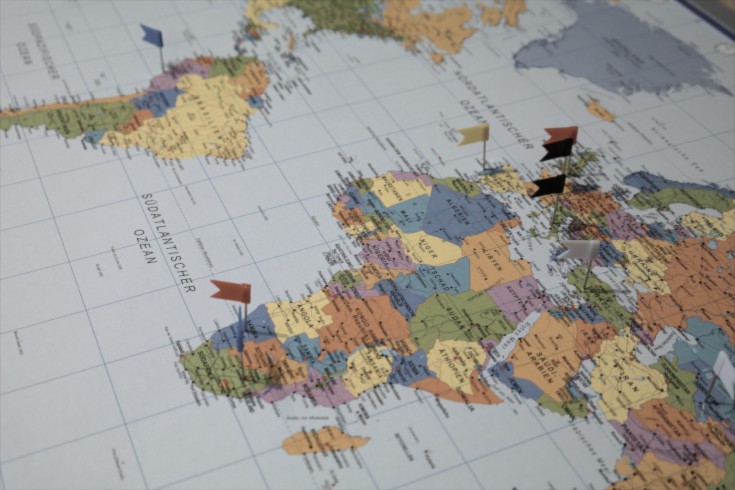 Mit Fähnchen markierte Städte auf einer Weltkarte